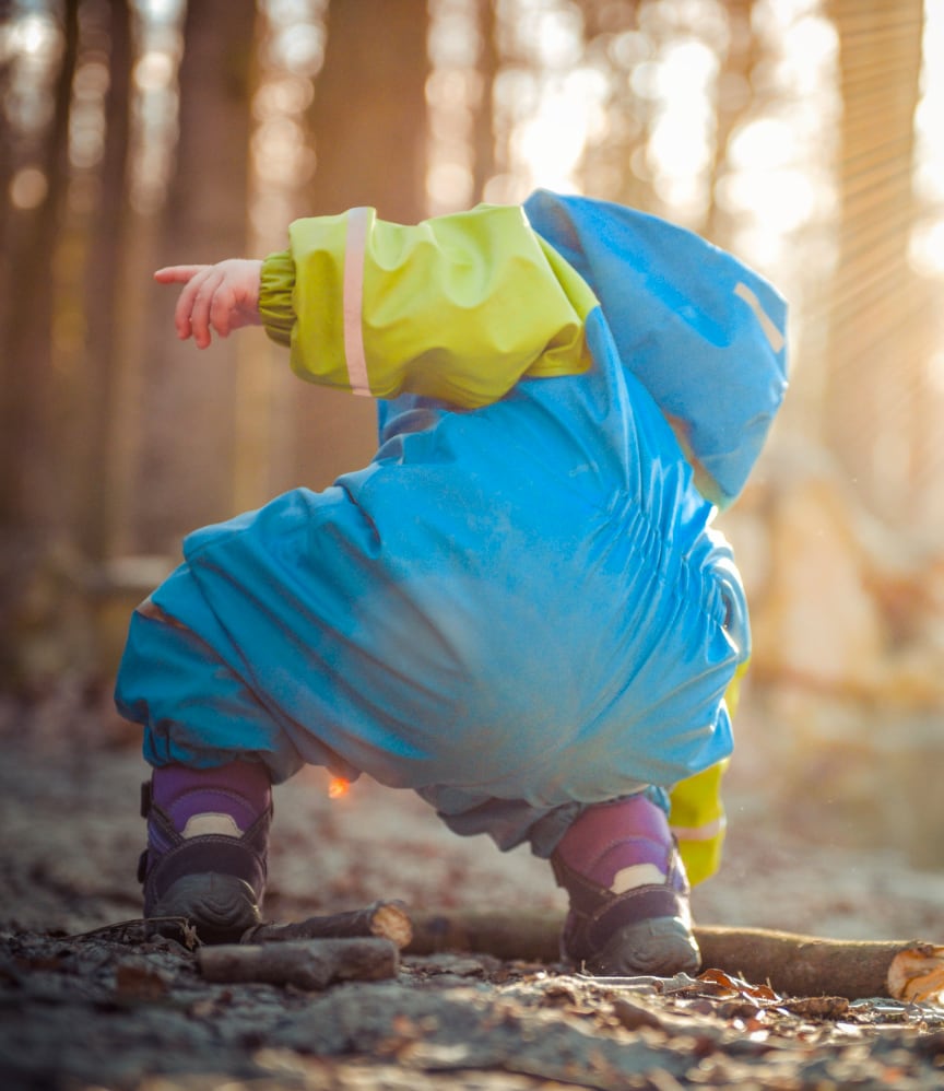 Child crouching in a forest