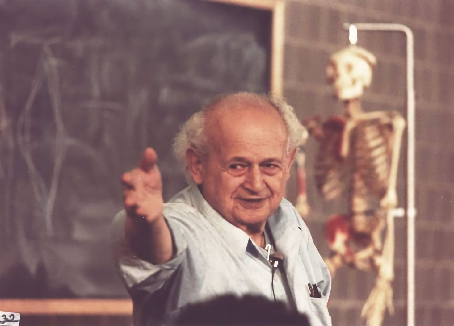 Moshe Feldenkrais teaching in front of a blackboard and skeleton